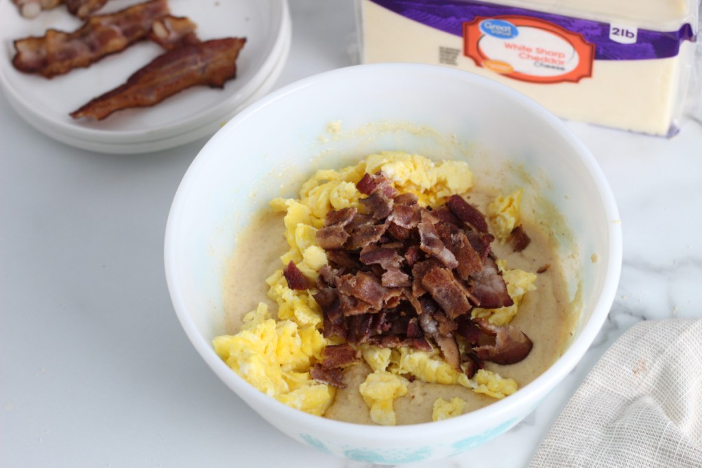 a bowl of waffle mix, scrambled eggs, and bacon 