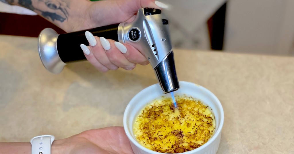 hand holding blow torch over bowl with eggs