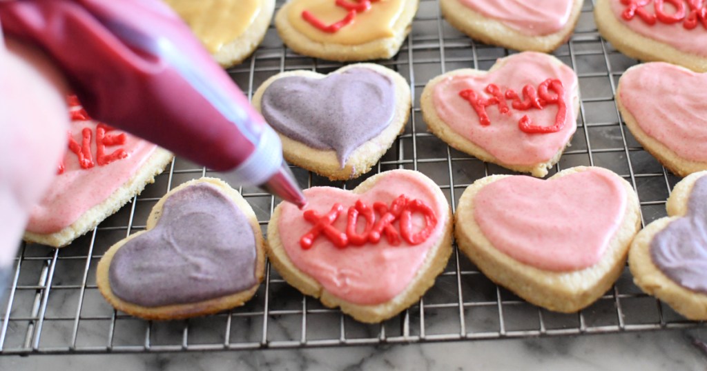 piping frosting on keto conversation heart sugar cookies