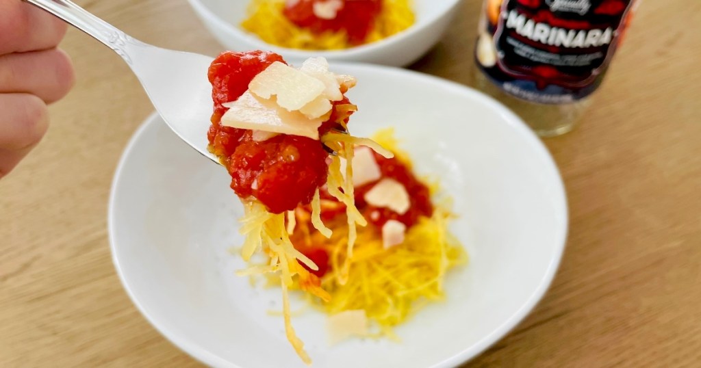 hand holding a fork with spaghetti squash and red pasta sauce