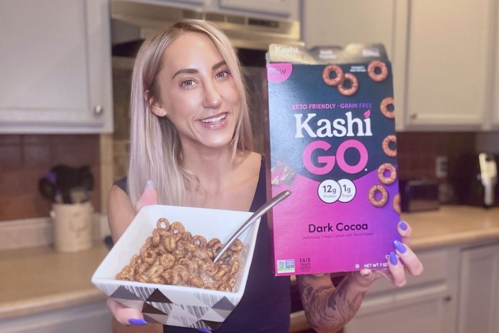 A woman holding a box of cereal and a bowl full of cereal