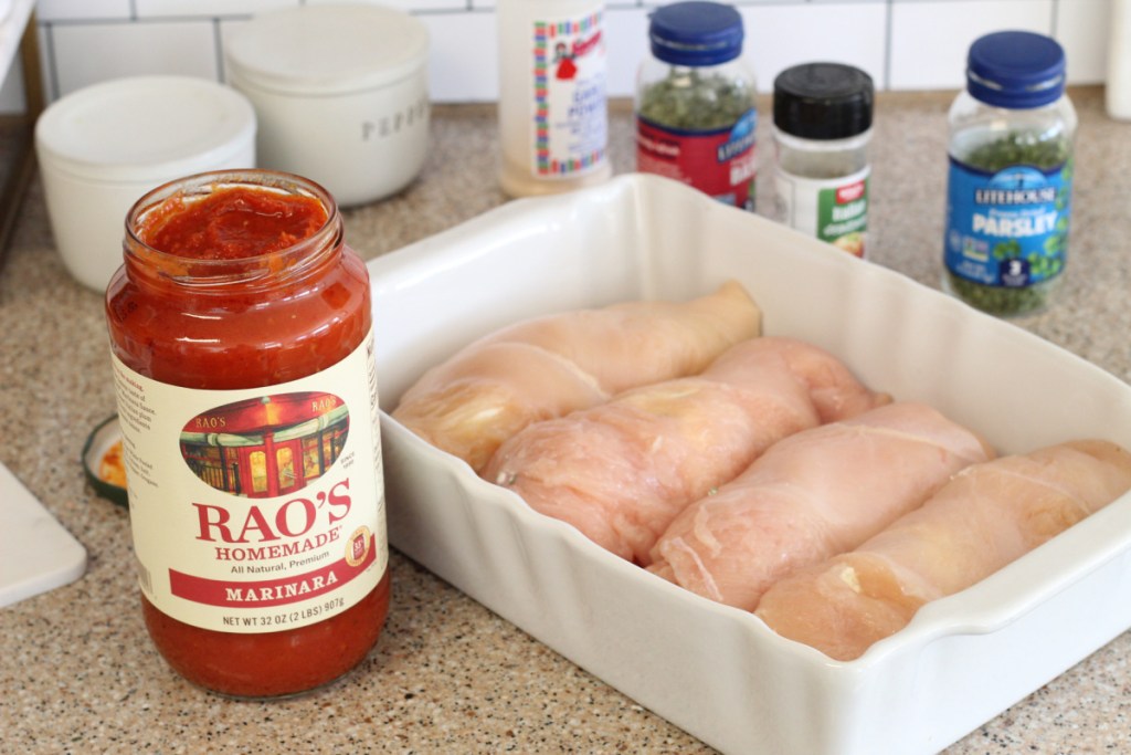 stuffed chicken in a casserole dish with marinara sauce on the side