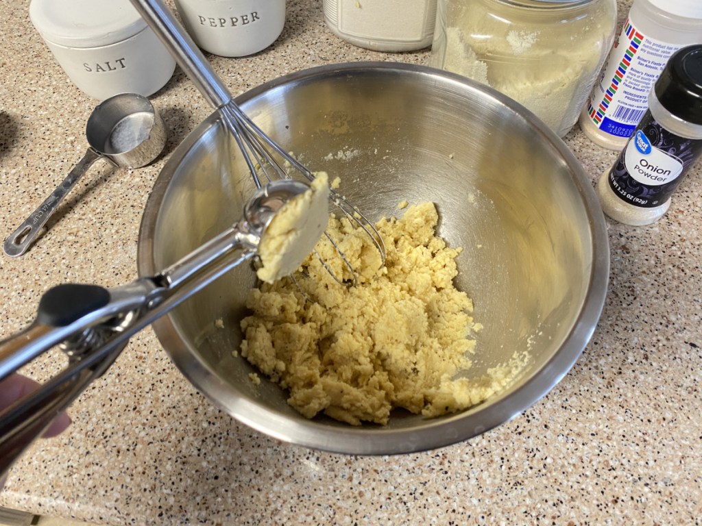 scooping hush puppy out of mixing bowl