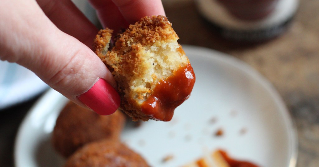 girl holding hushpuppy with ketchup