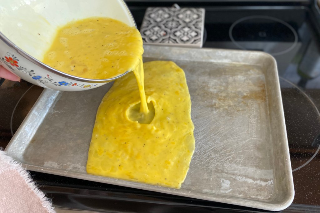 pouring egg batter on a sheet pan
