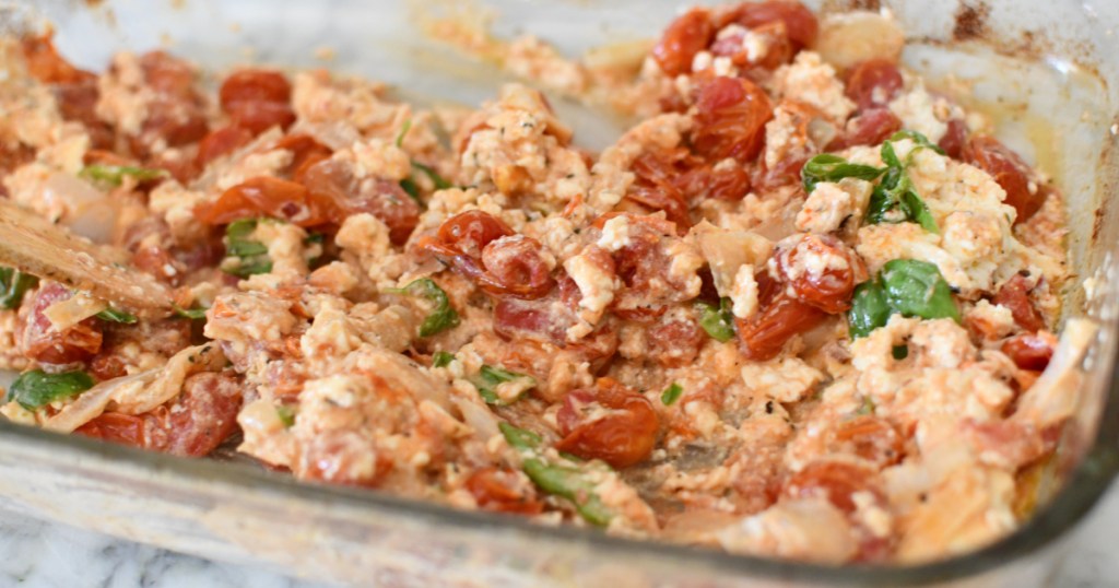 adding fresh basil to baked feta cheese