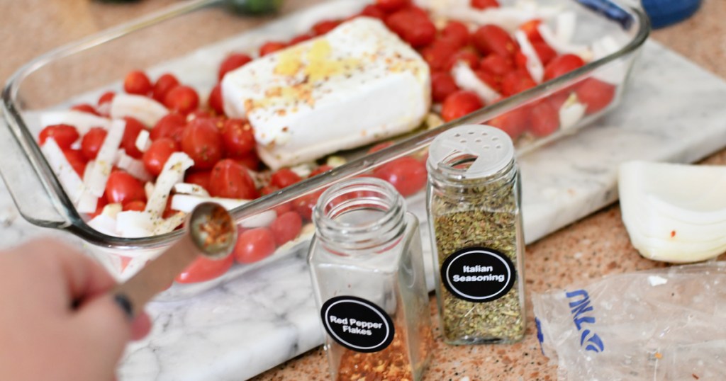 adding seasoning to baked feta and tomatoes