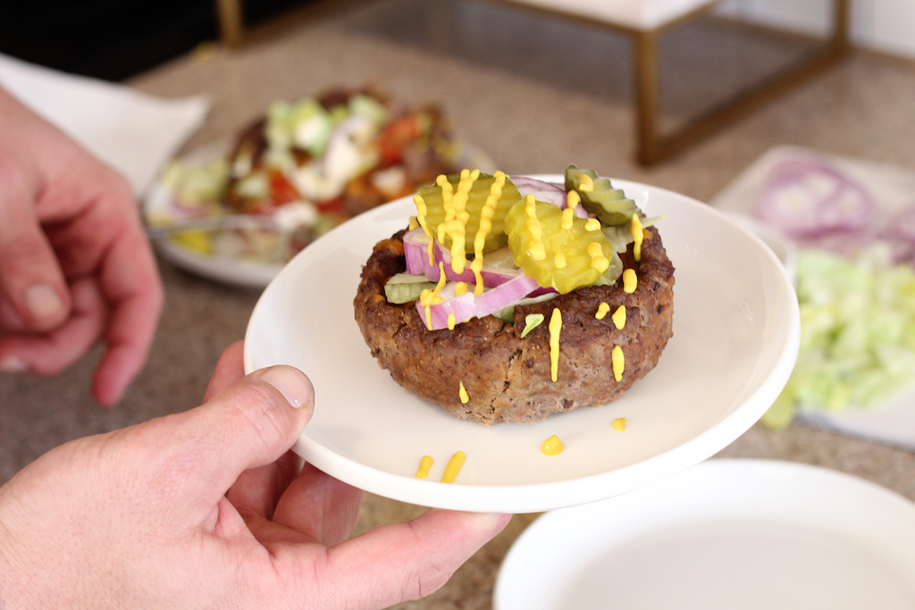 holding hamburger bowl with toppings 