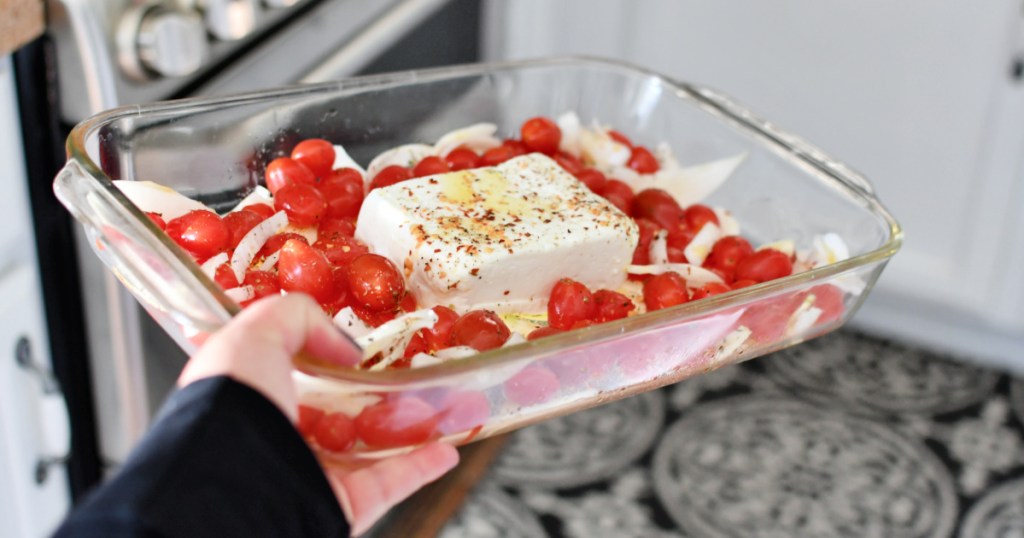 holding a casserole dish with feta and tomatoes 