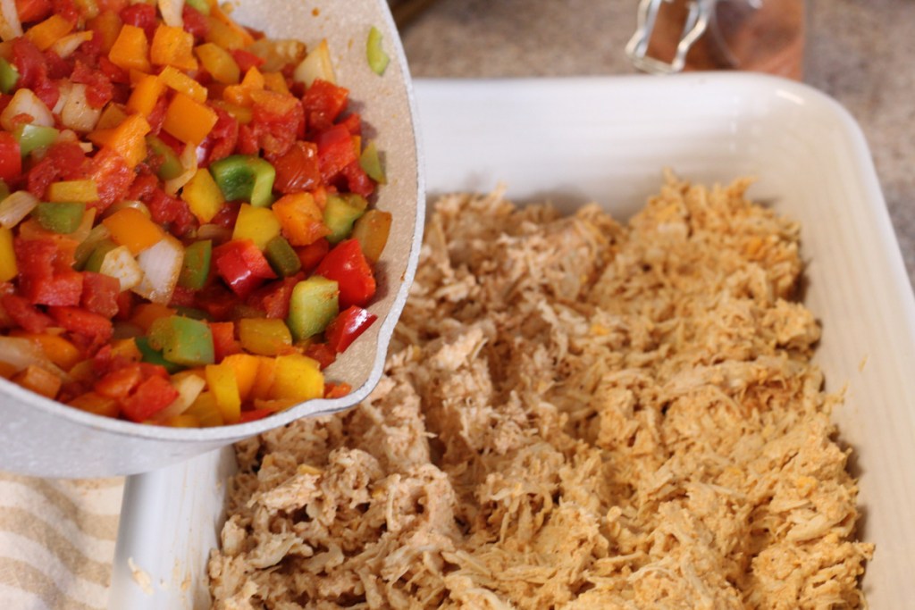 adding sauteed peppers to chicken casserole dish