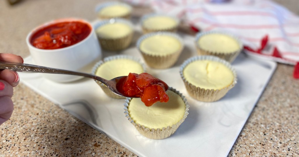 adding strawberries to the top of a keto mini cheesecake