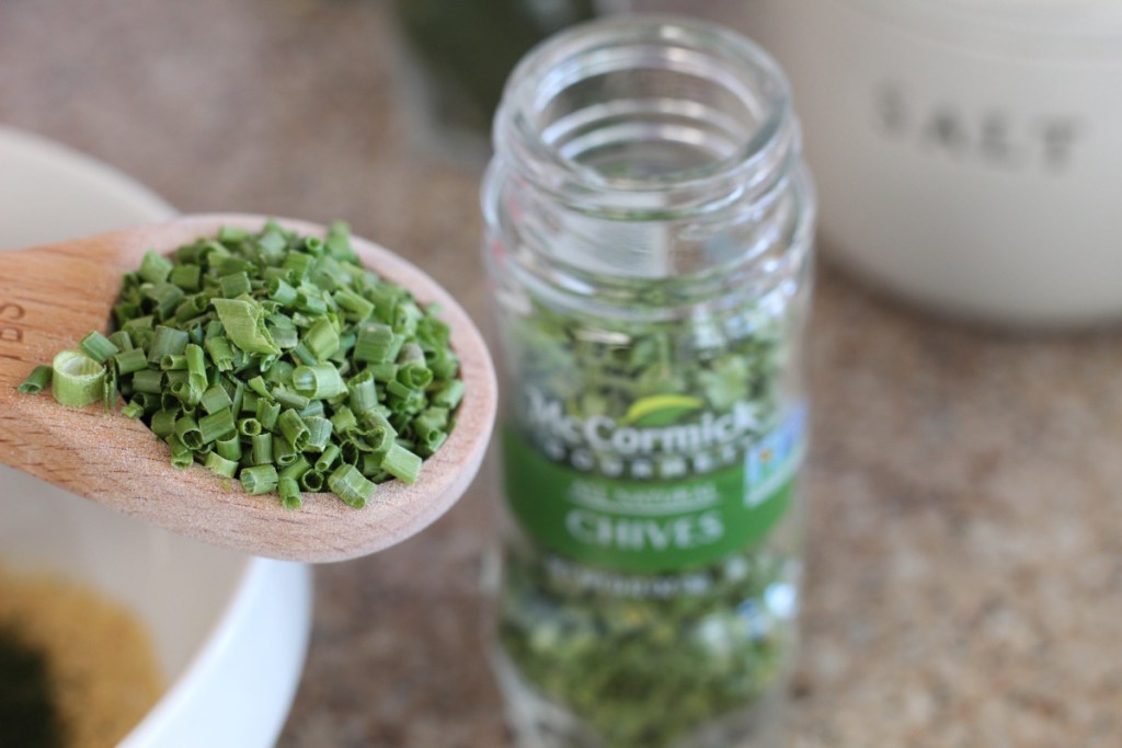 adding dried chives to mixing bowl