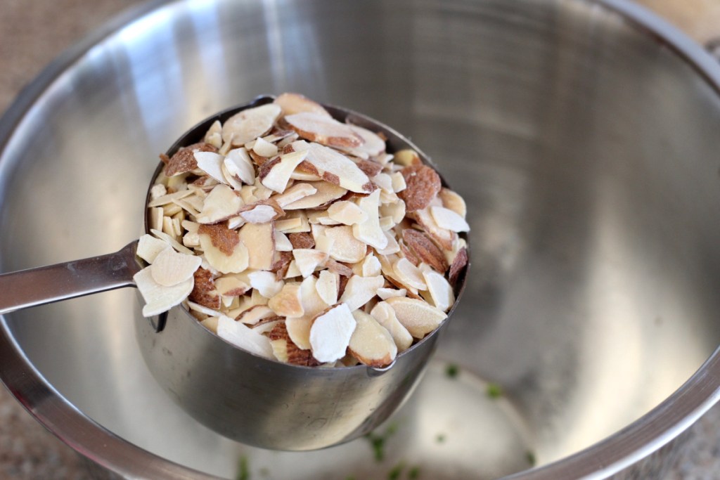 a cup of almonds being adding to mixing bowl