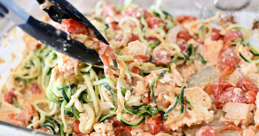 mixing zoodles with baked feta sauce