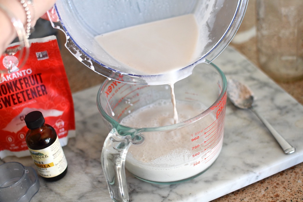 pouring almond milk into glass measuring cup