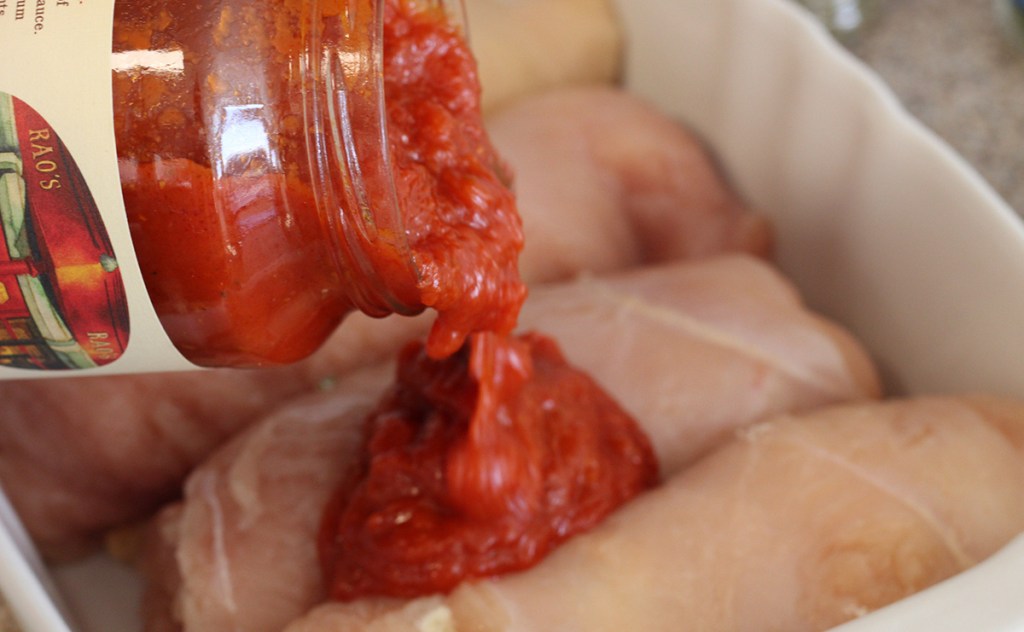 pouring marinara sauce on chicken