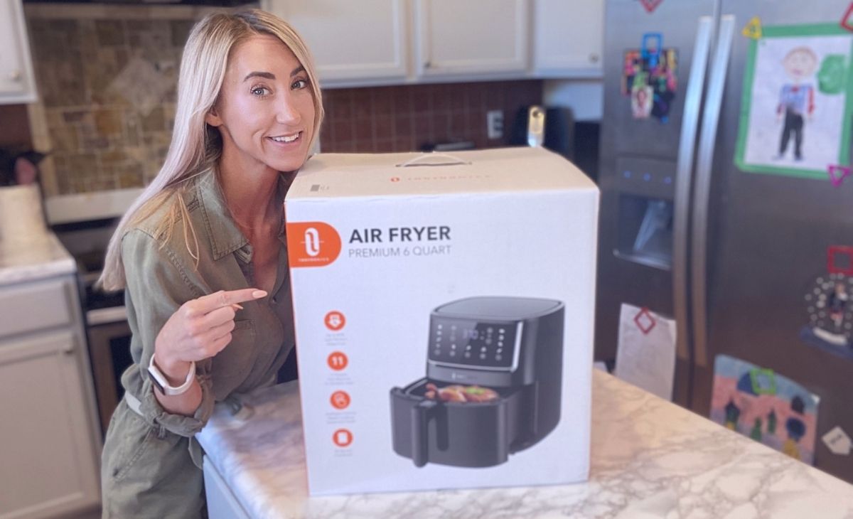 A woman pointing to an air fryer box on a counter