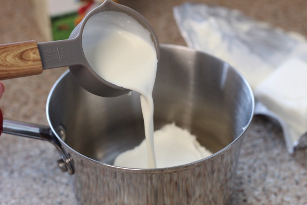 pouring heavy cream into saucepan
