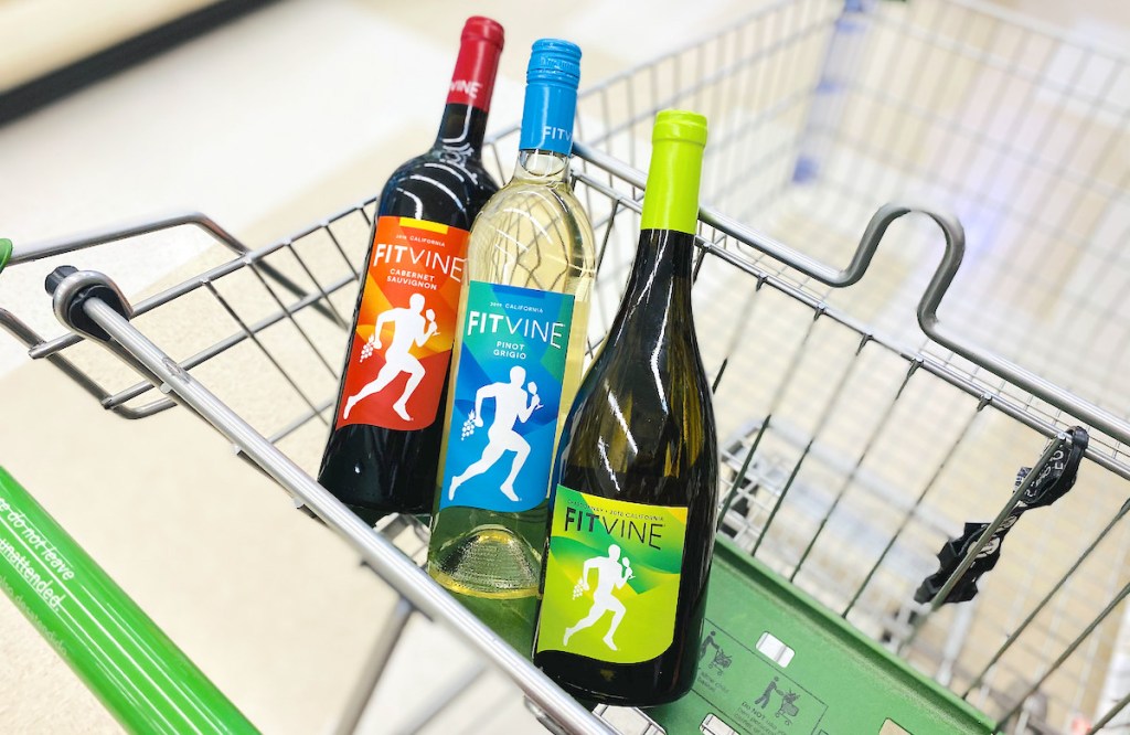 three bottles of wine in top of grocery cart