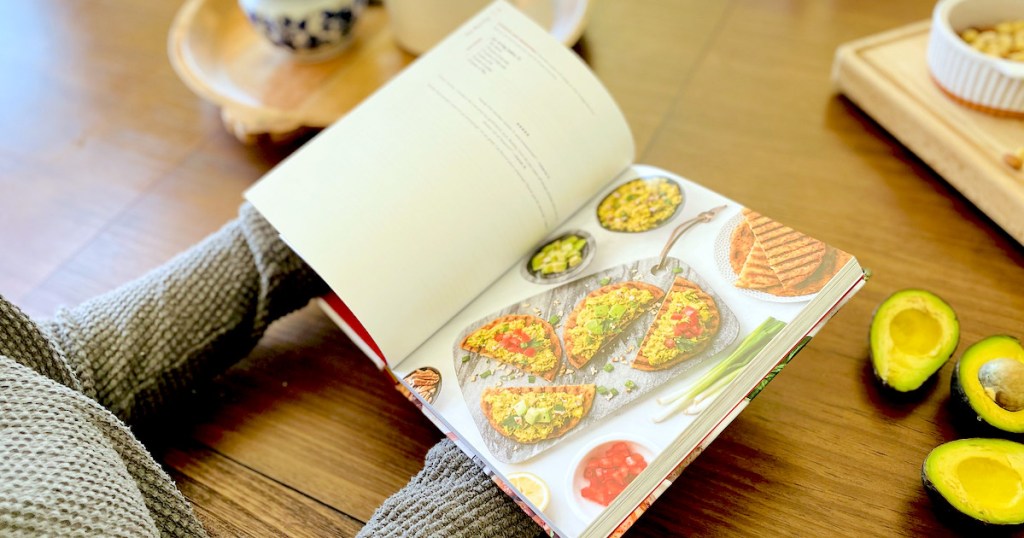 person holding keto cookbook with pita recipe on paper