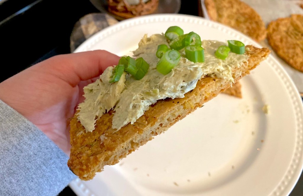 hand holding half of keto pita break over white plate