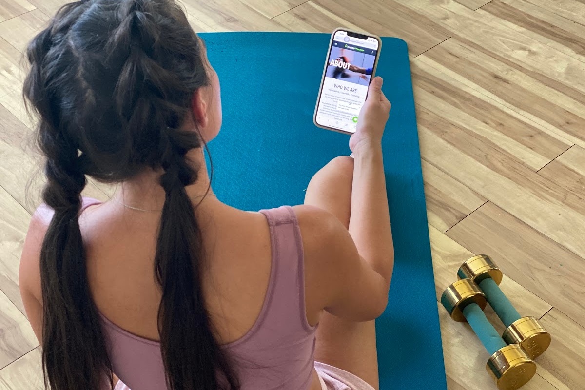 woman sitting on mat and holding phone with inside tracker app