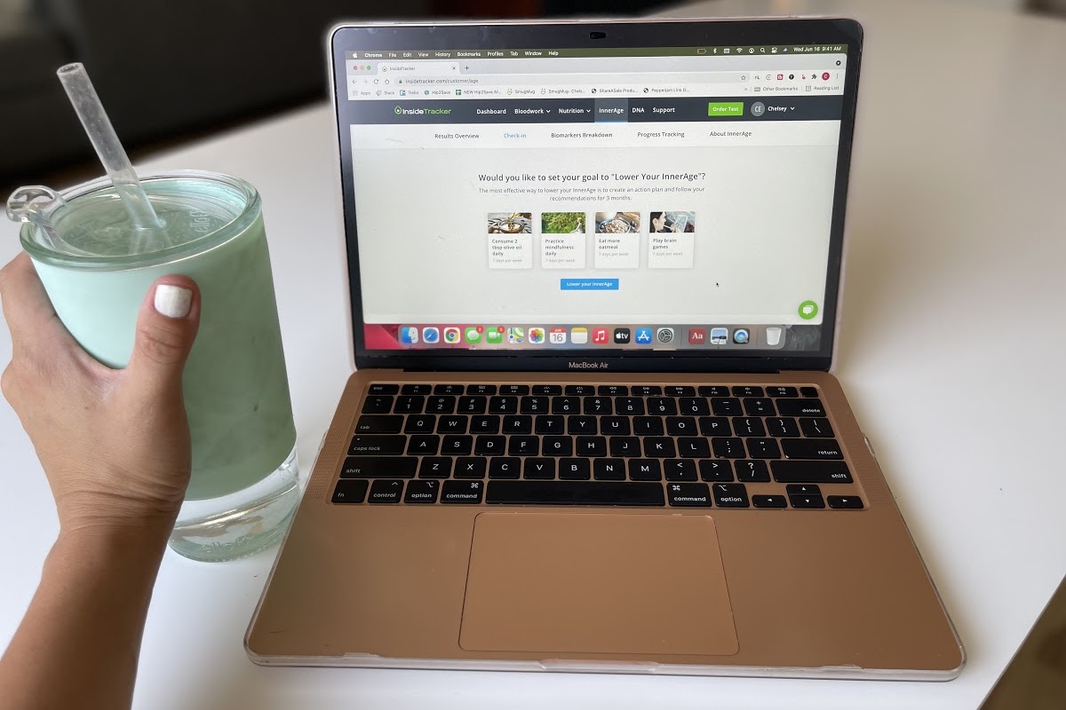hand holding a green tumbler beside laptop
