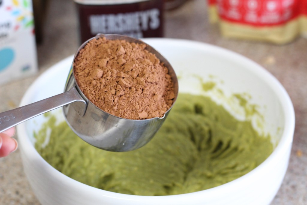 adding cocoa to smashed avocado