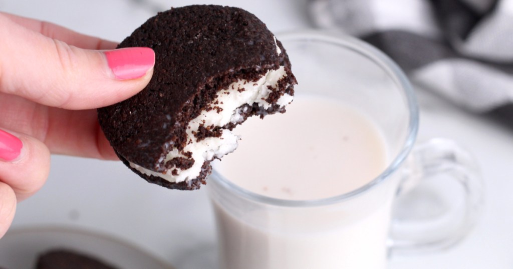 holding keto Oreo cookies with cup of almond milk