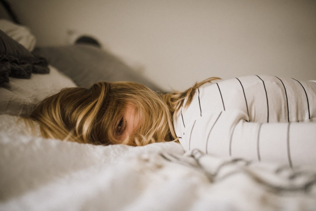 woman lying awake face down on bed