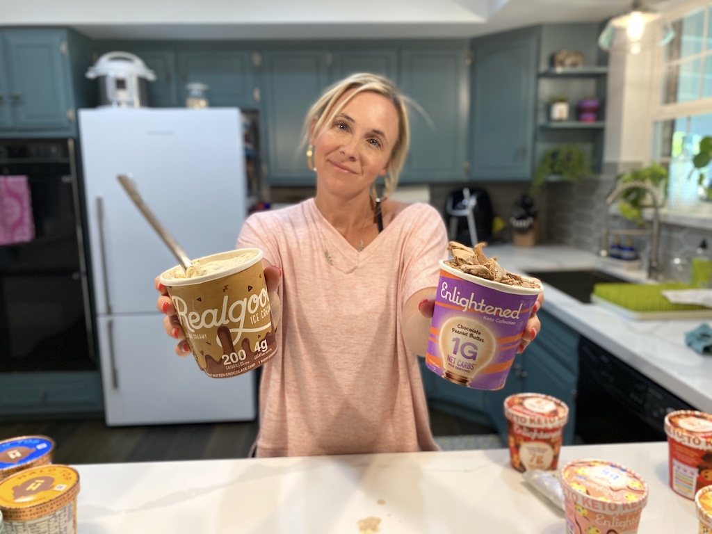 woman holding pints of keto ice cream in each hand in kitchen