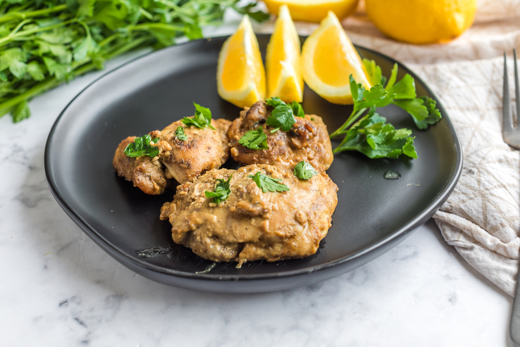 keto lemon chicken thighs on plate with fresh lemon slices 