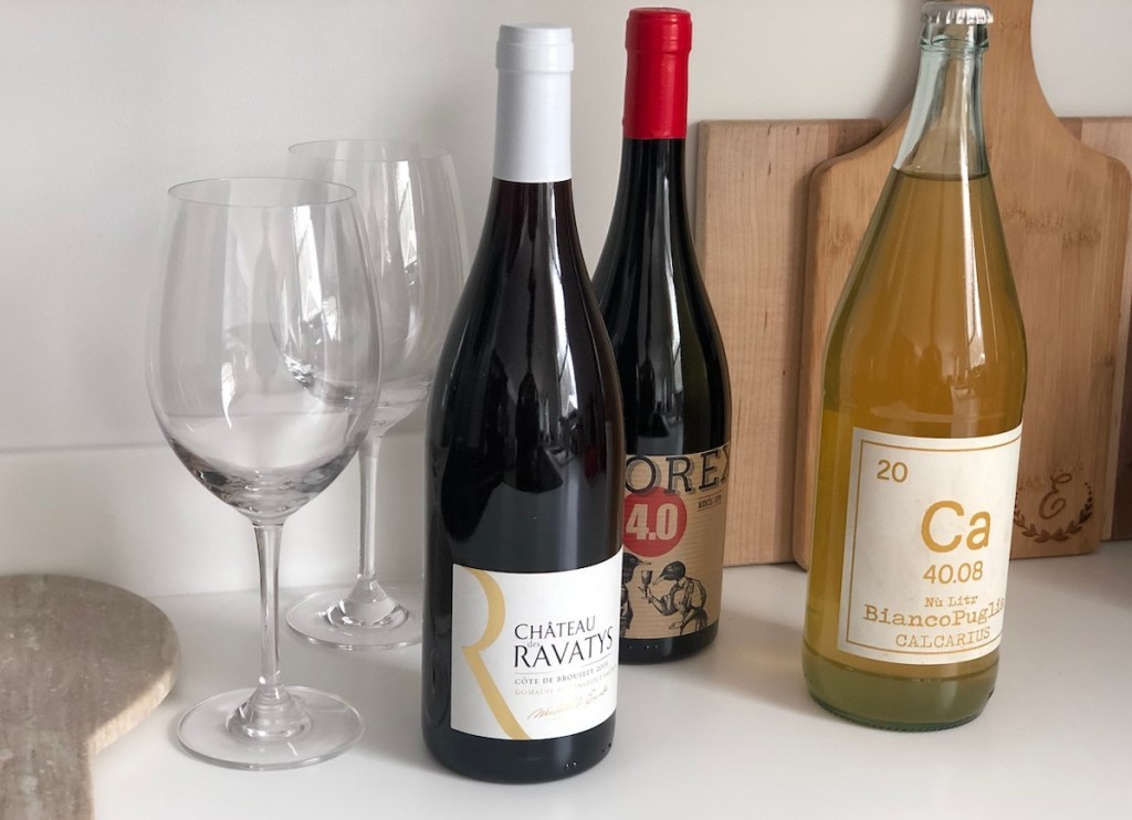 bottles of red and white wines with glasses on kitchen counter