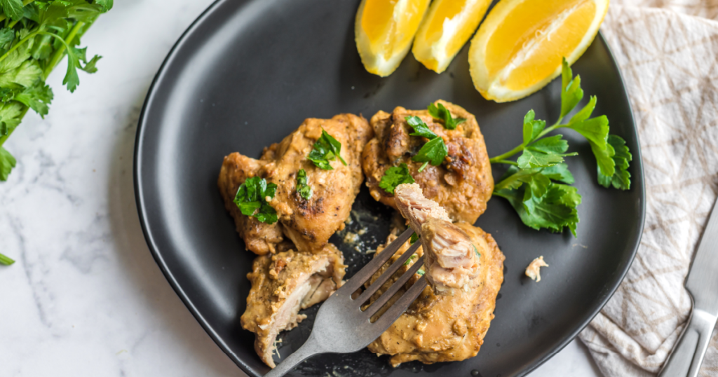 lemon chicken thighs on plate with fresh lemon slices 