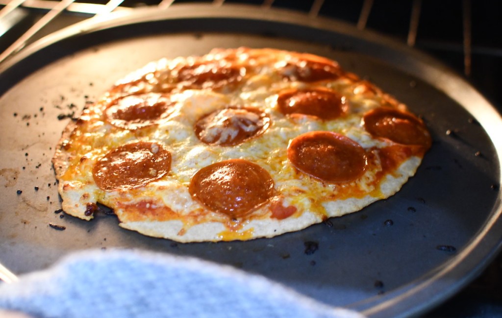 pepperoni pizza baking in oven on round sheet pan