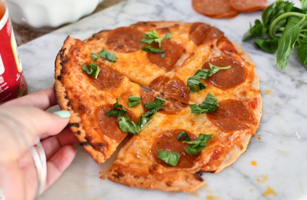 hand holding slice of pepperoni keto pizza crust 