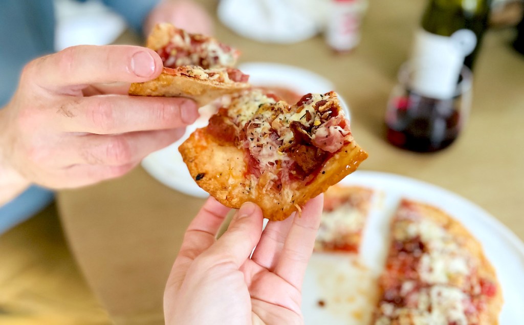 two people putting slices of pizza together