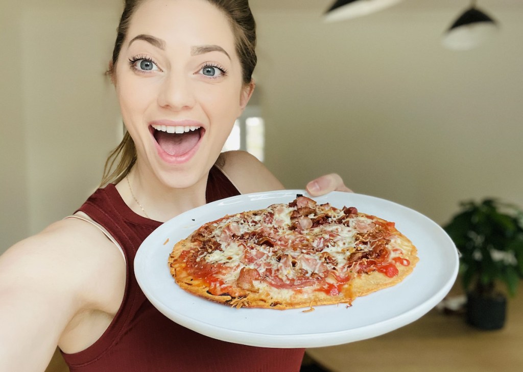 woman holding plate with personal keto pizza crust on it