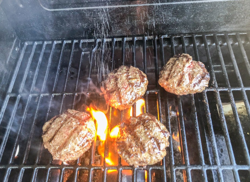 Seasoning burgers on grill