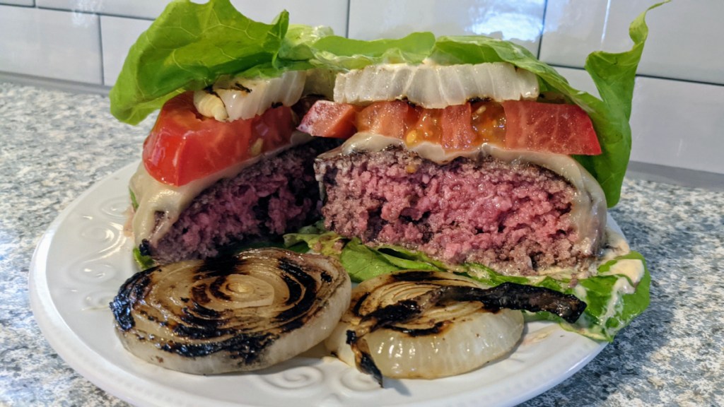 lettuce wrapped burger cut in half on a plate