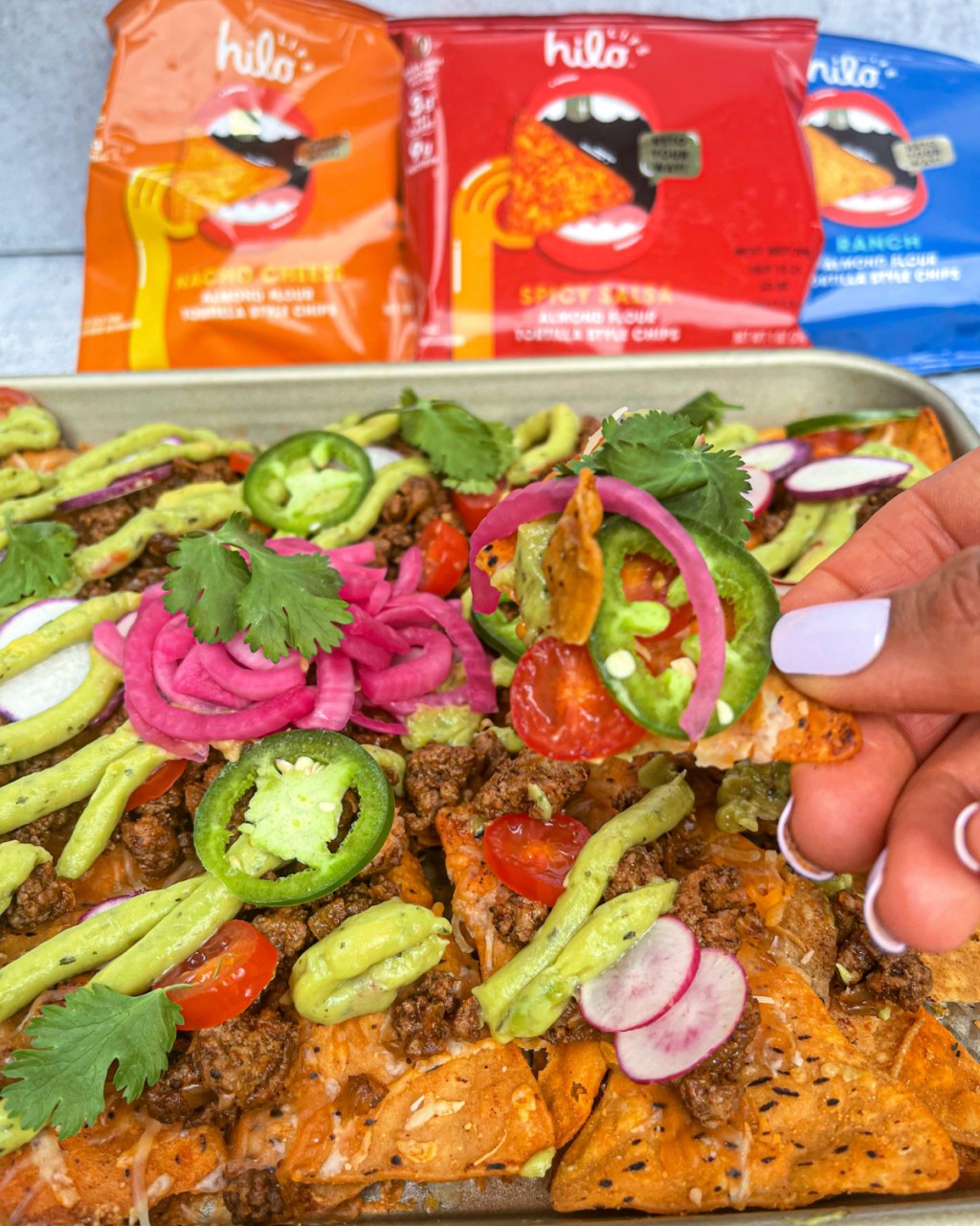 hand holding keto sheet pan nachos with HILO LIFE chips