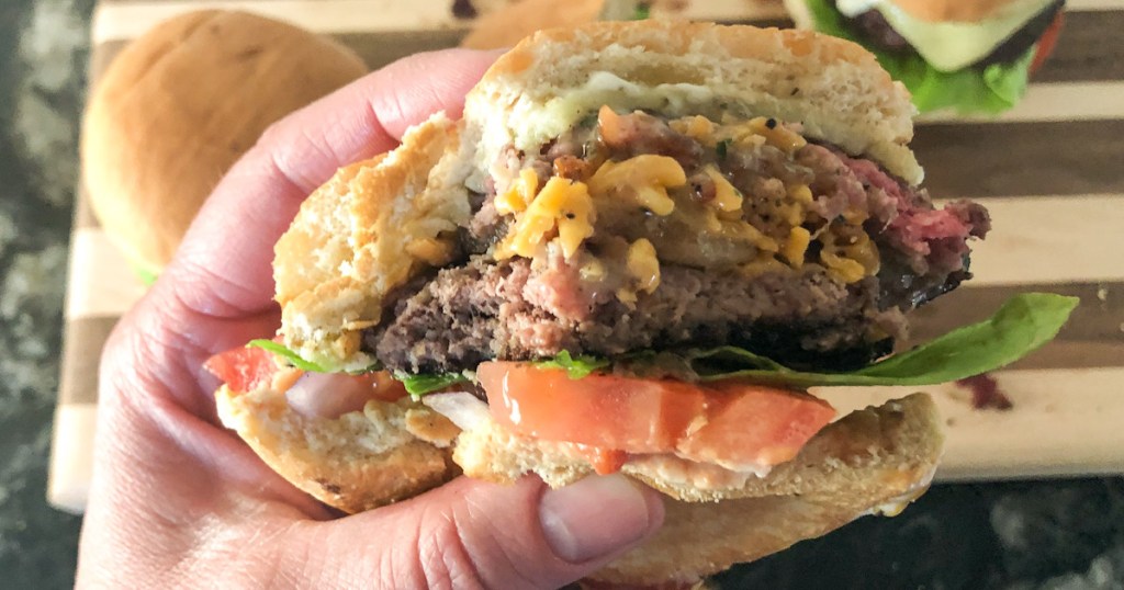 hand hold a burger with a bite out of it