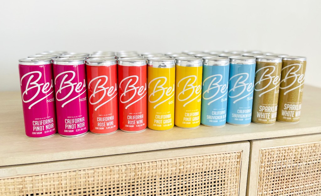 row of rainbow canned wine sitting on caned table