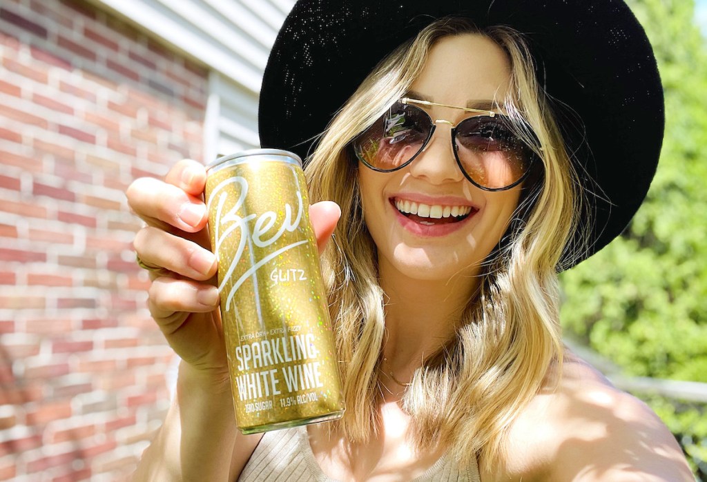 woman holding up gold bev canned wine