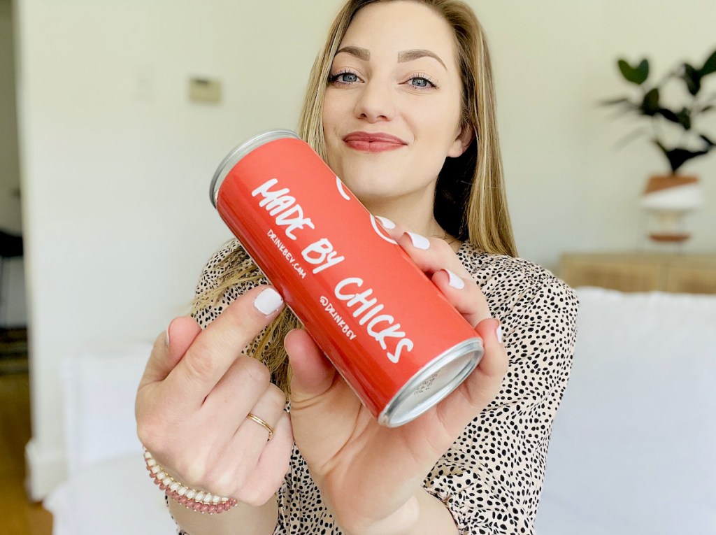 woman pointing to made by chicks wording on drink