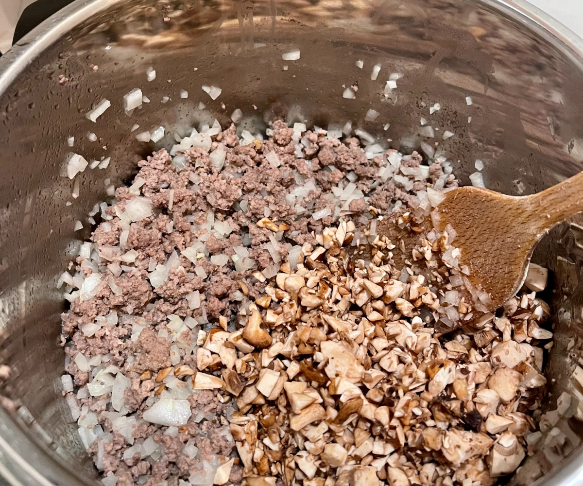 ground beef cooking with chopped onions and mushrooms
