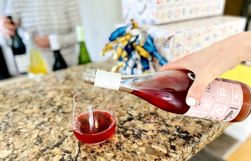 hand pouring rose wine into glass at party on granite kitchen counter
