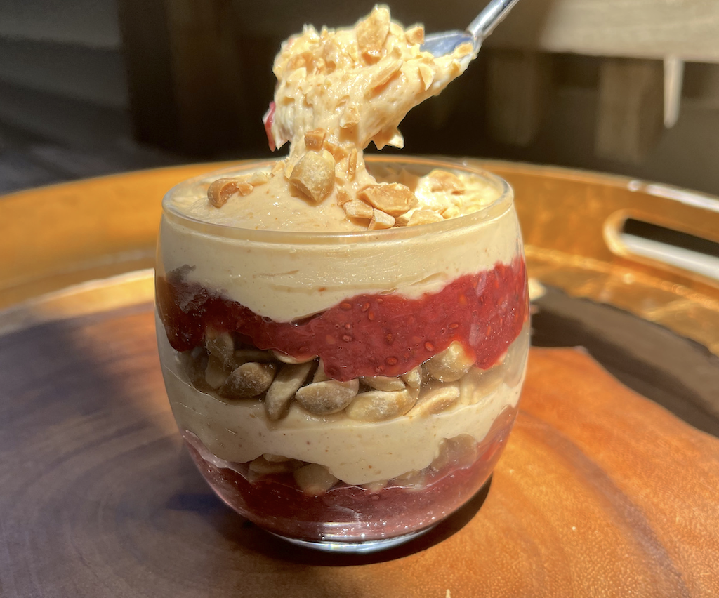 taking bit of whipped peanut butter and jelly parfait with peanuts
