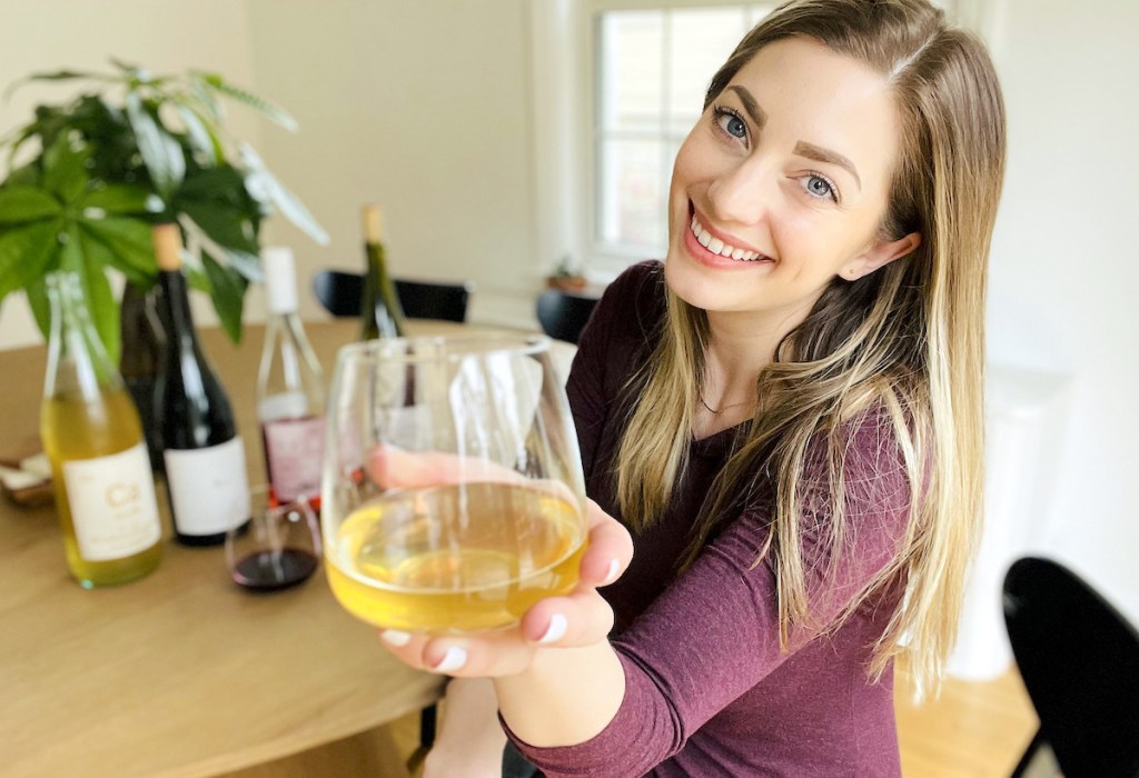 woman holding a glass of white wine in front of camera