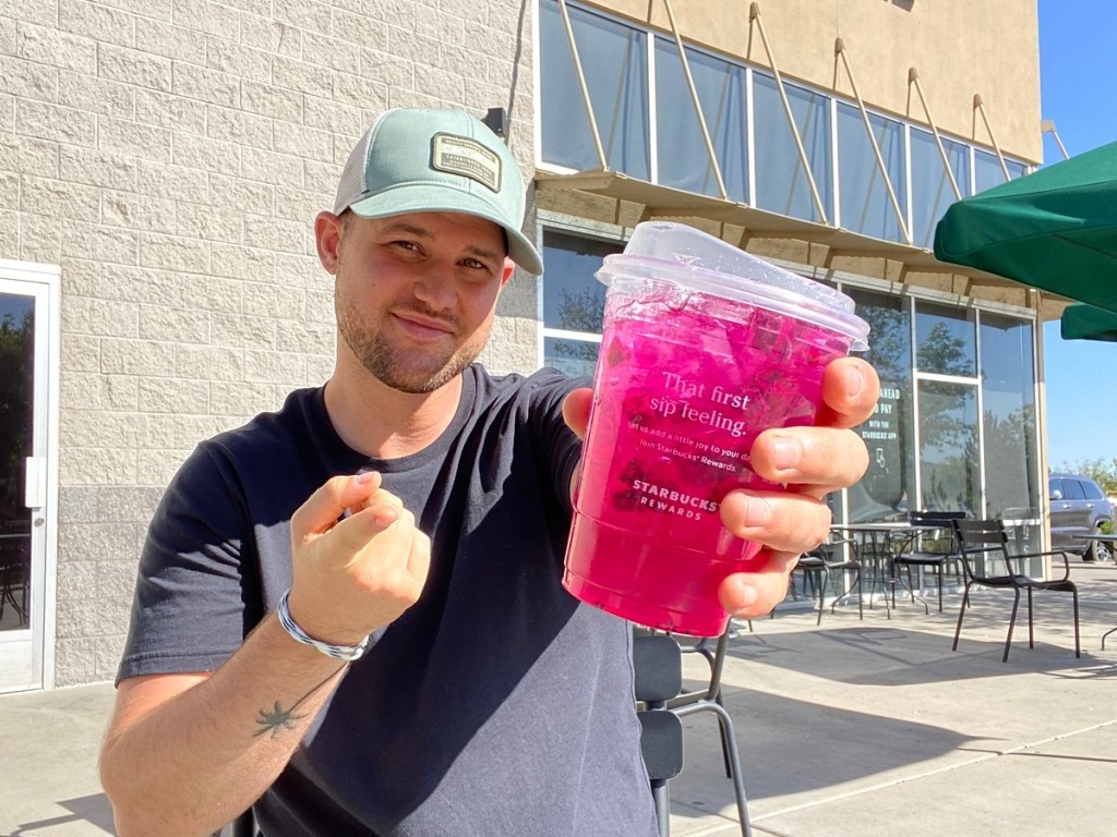 man holding pink starbucks drink
